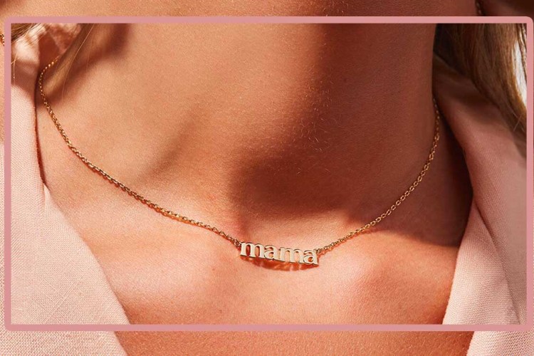 A woman wearing a necklace that spells "mama," a great piece o jewelry to gift this Mother's Day