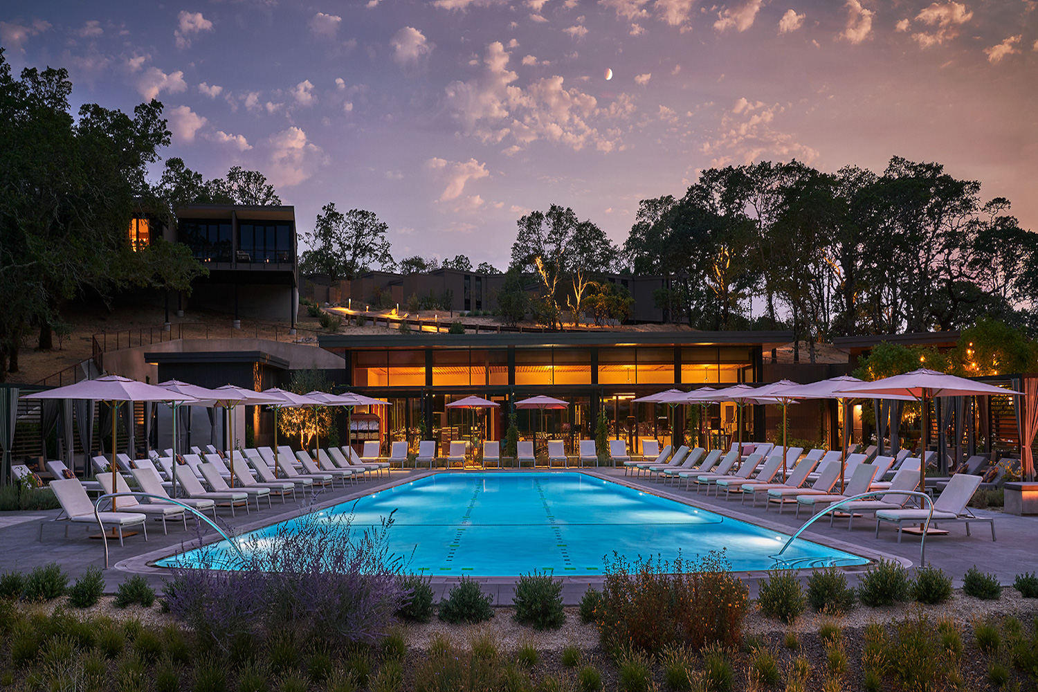 outdoor pool with wide seating area and nice sunset behind it