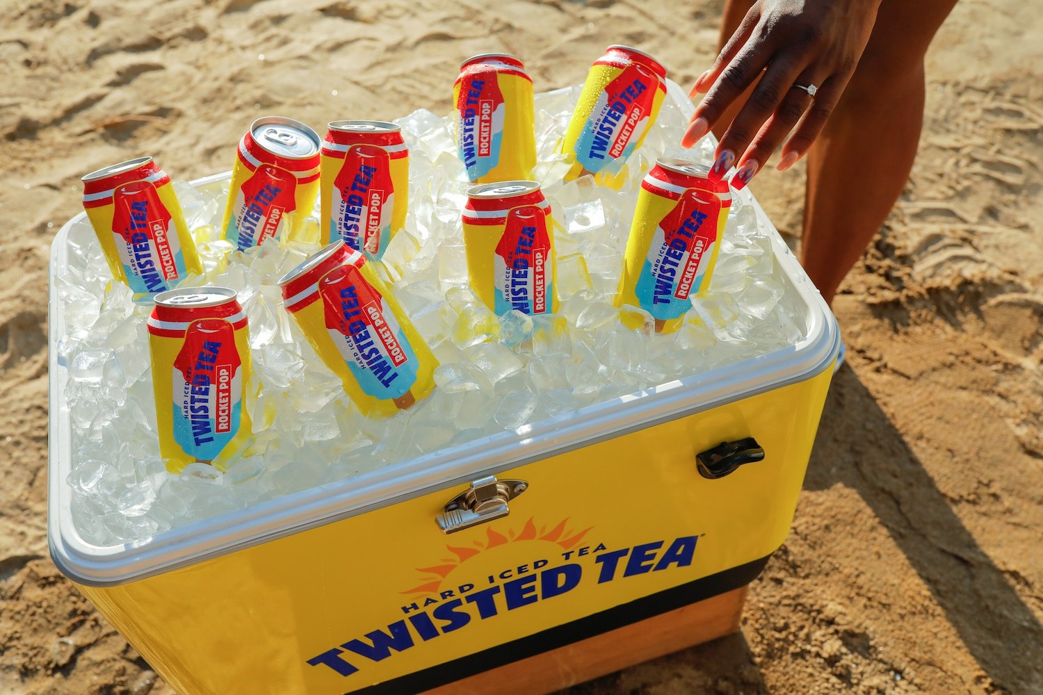 a cooler full of ice and Twister Tea Rocket Pop on a beach
