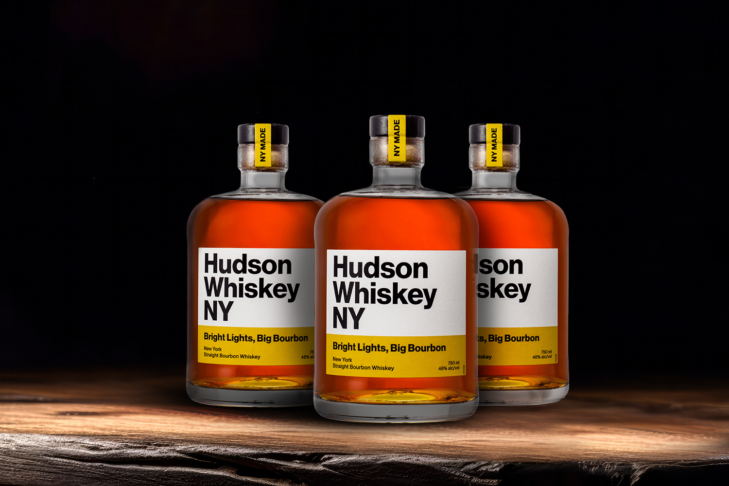 3 bottles of hudson whiskey bourbon on a wooden table
