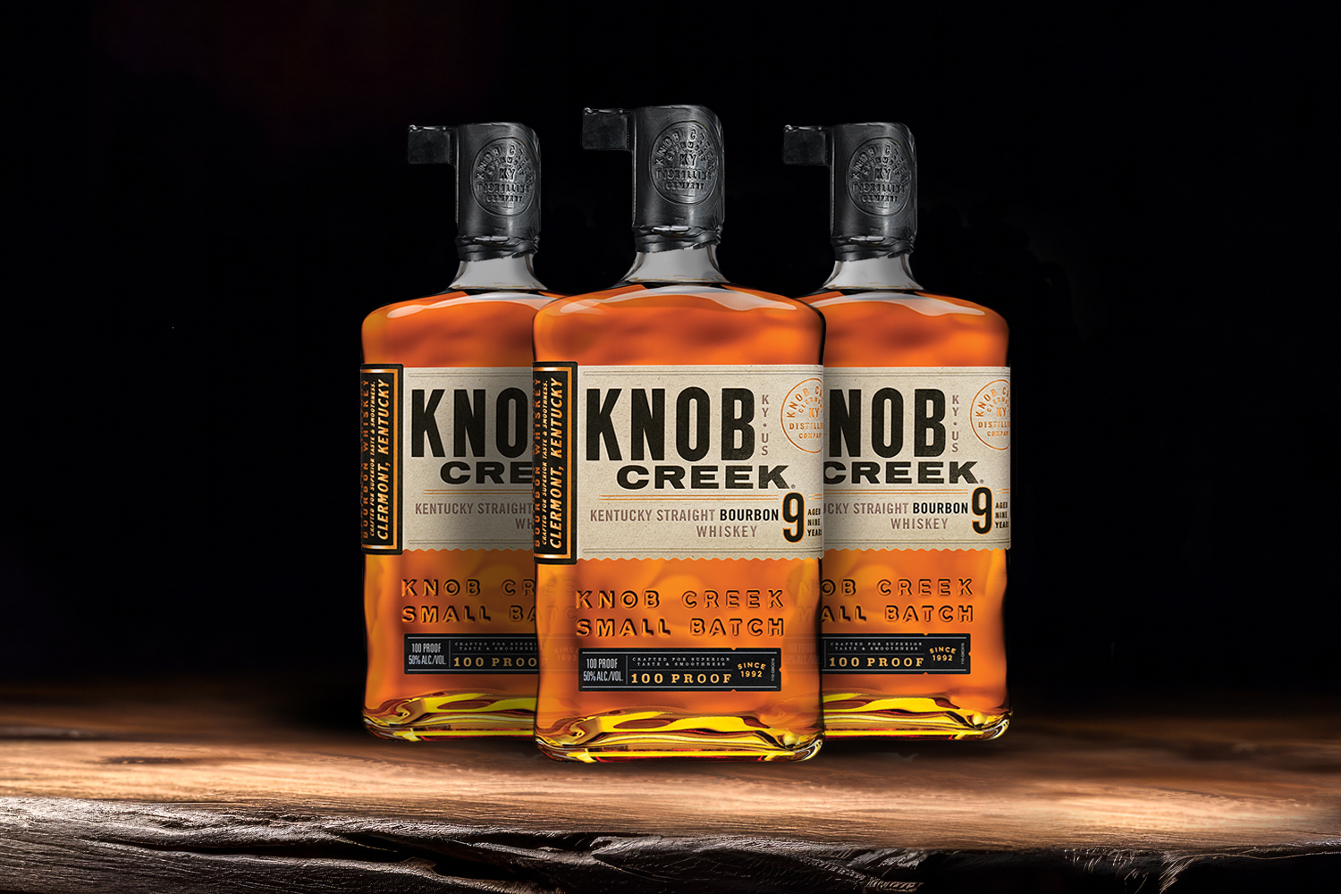 3 bottles of knob creek bourbon on a wooden table