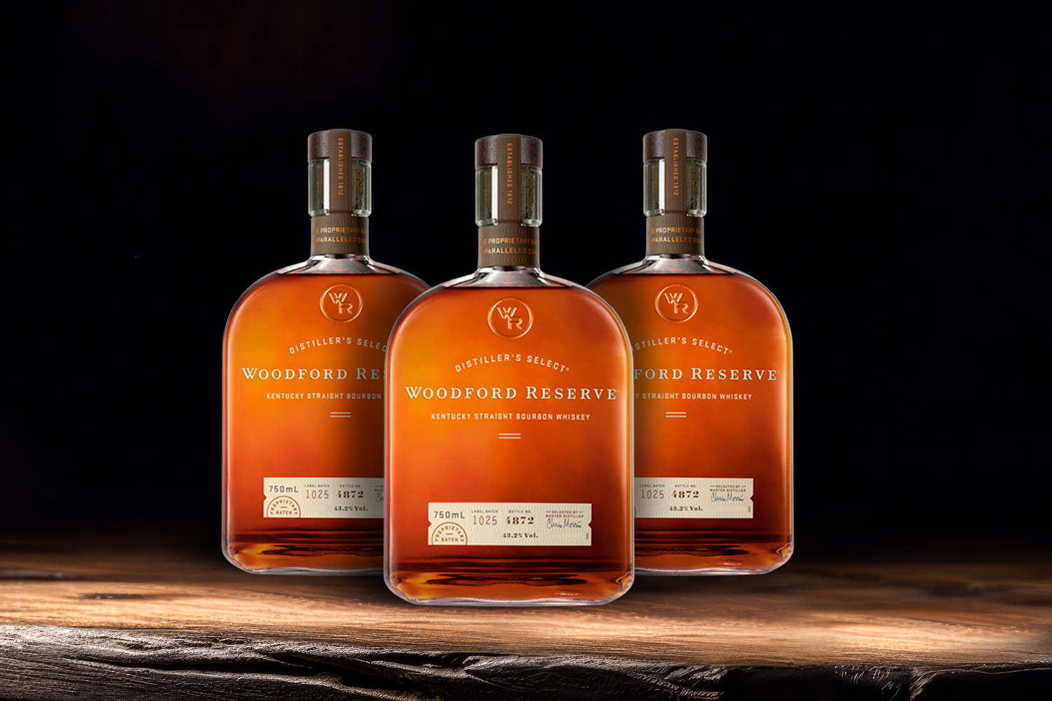 3 bottles of woodford reserve on a wooden table