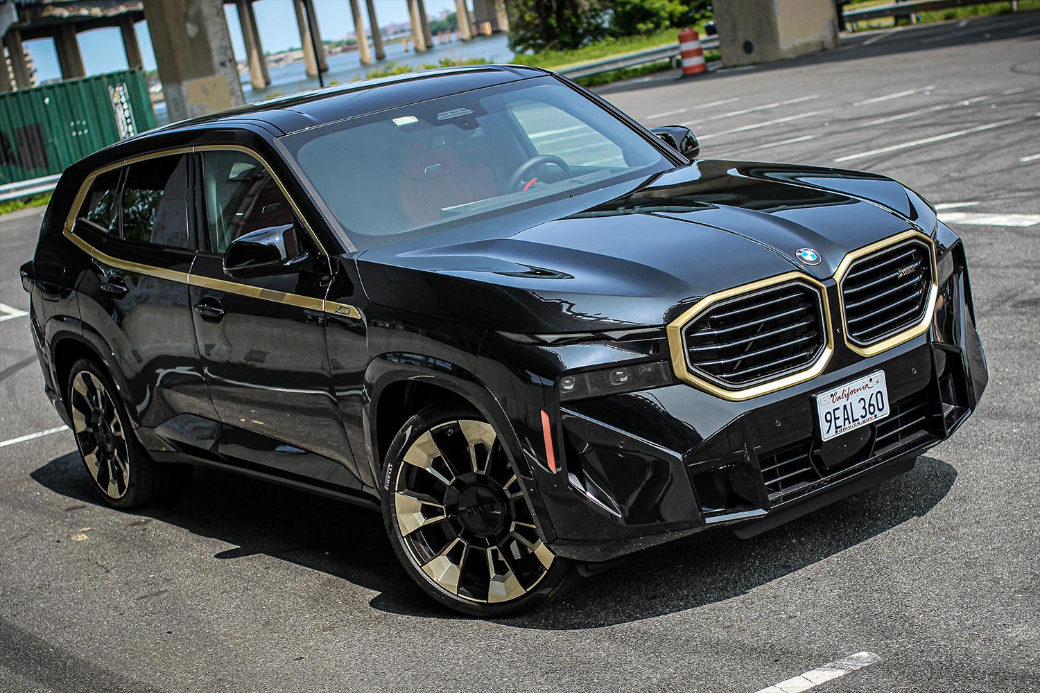 A front three-quarters photo of the 2023 BMW XM SUV with gold accents and a black paint job
