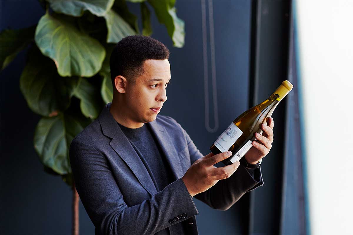 Thatcher Baker-Briggs, a 31-year old wine consultant with A-level celebrity clients, looking at a bottle of wine