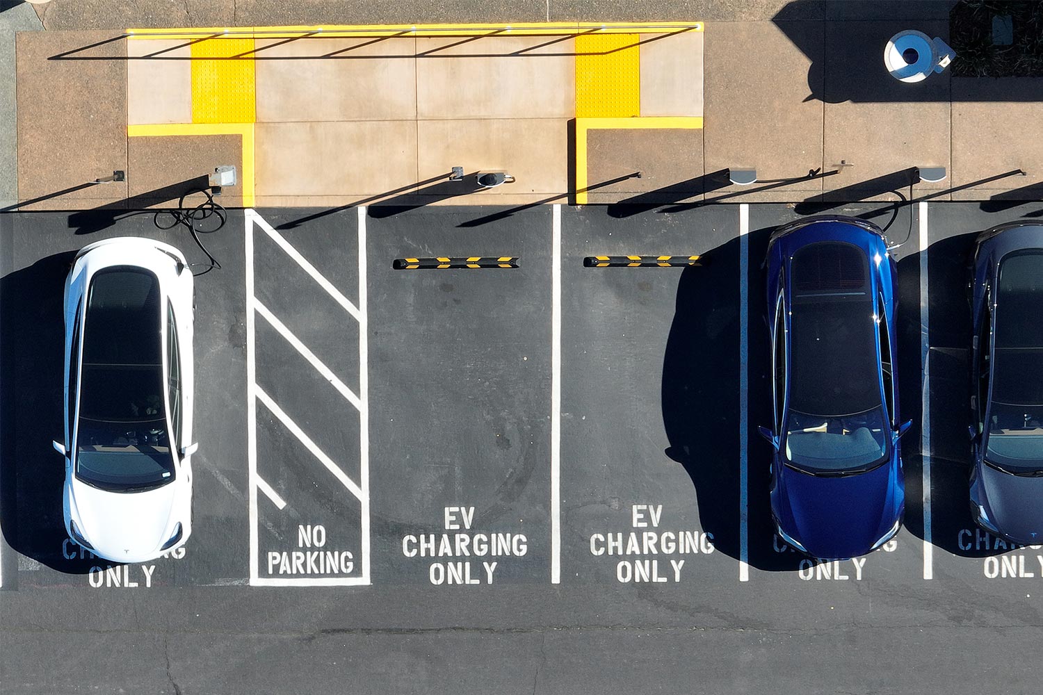 An aerial shot of electric cars charging in EV-only parking spaces. We discuss the term "bricked" as it relates to EVs.