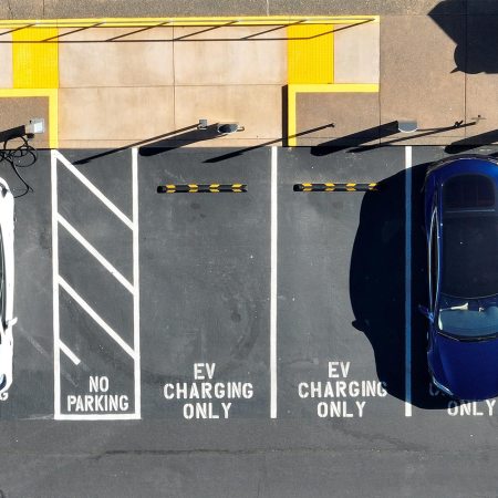 An aerial shot of electric cars charging in EV-only parking spaces. We discuss the term "bricked" as it relates to EVs.
