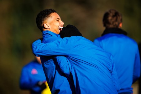 Two men in blue jackets laughing and embracing.