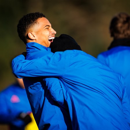 Two men in blue jackets laughing and embracing.