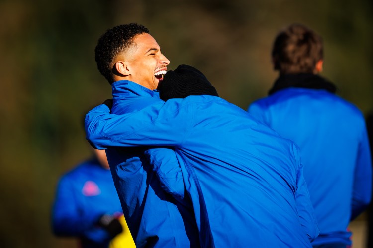 Two men in blue jackets laughing and embracing.