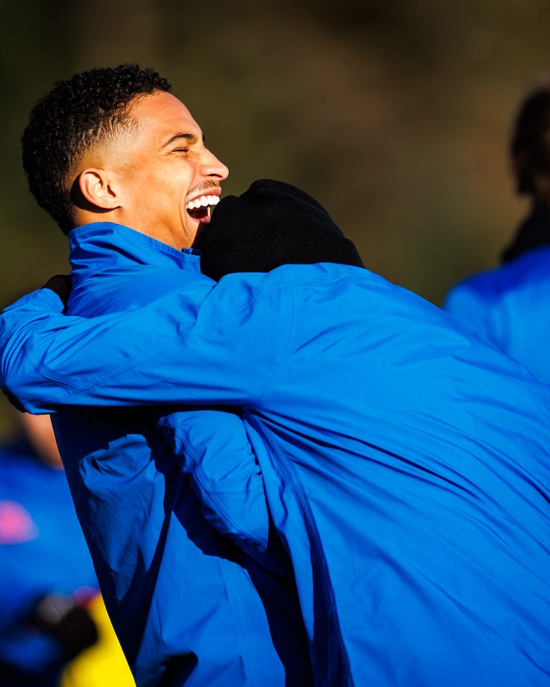Two men in blue jackets laughing and embracing.