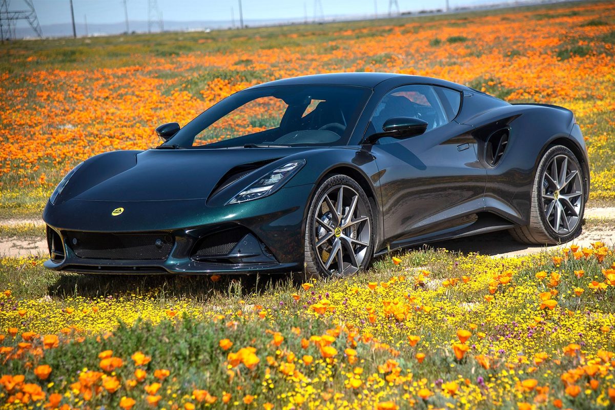 The new Lotus Emira, sitting in a field of wildflowers. We tested and reviewed the last gas-powered Lotus.