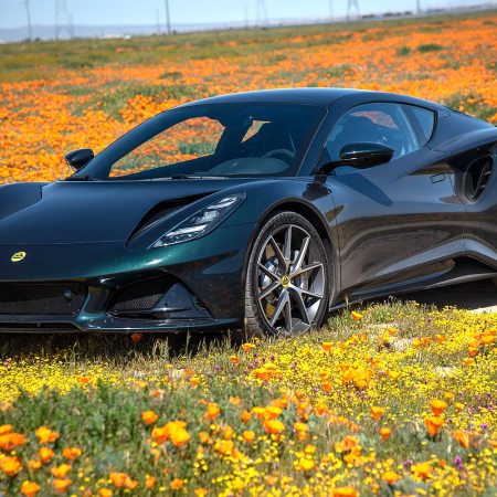 The new Lotus Emira, sitting in a field of wildflowers. We tested and reviewed the last gas-powered Lotus.