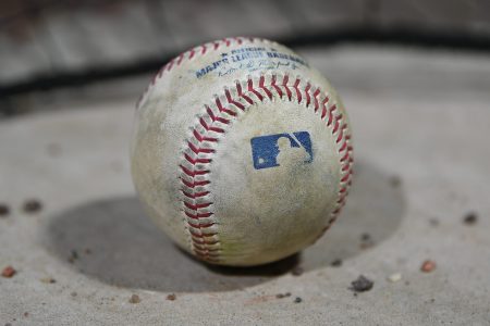 The Major League Baseball logo on a baseball on the dugout steps.