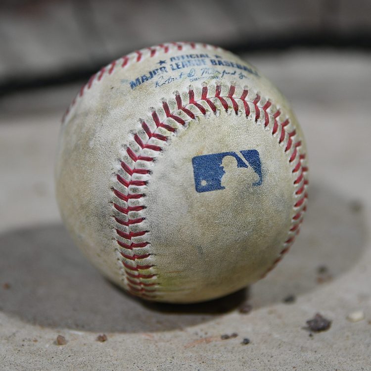 The Major League Baseball logo on a baseball on the dugout steps.