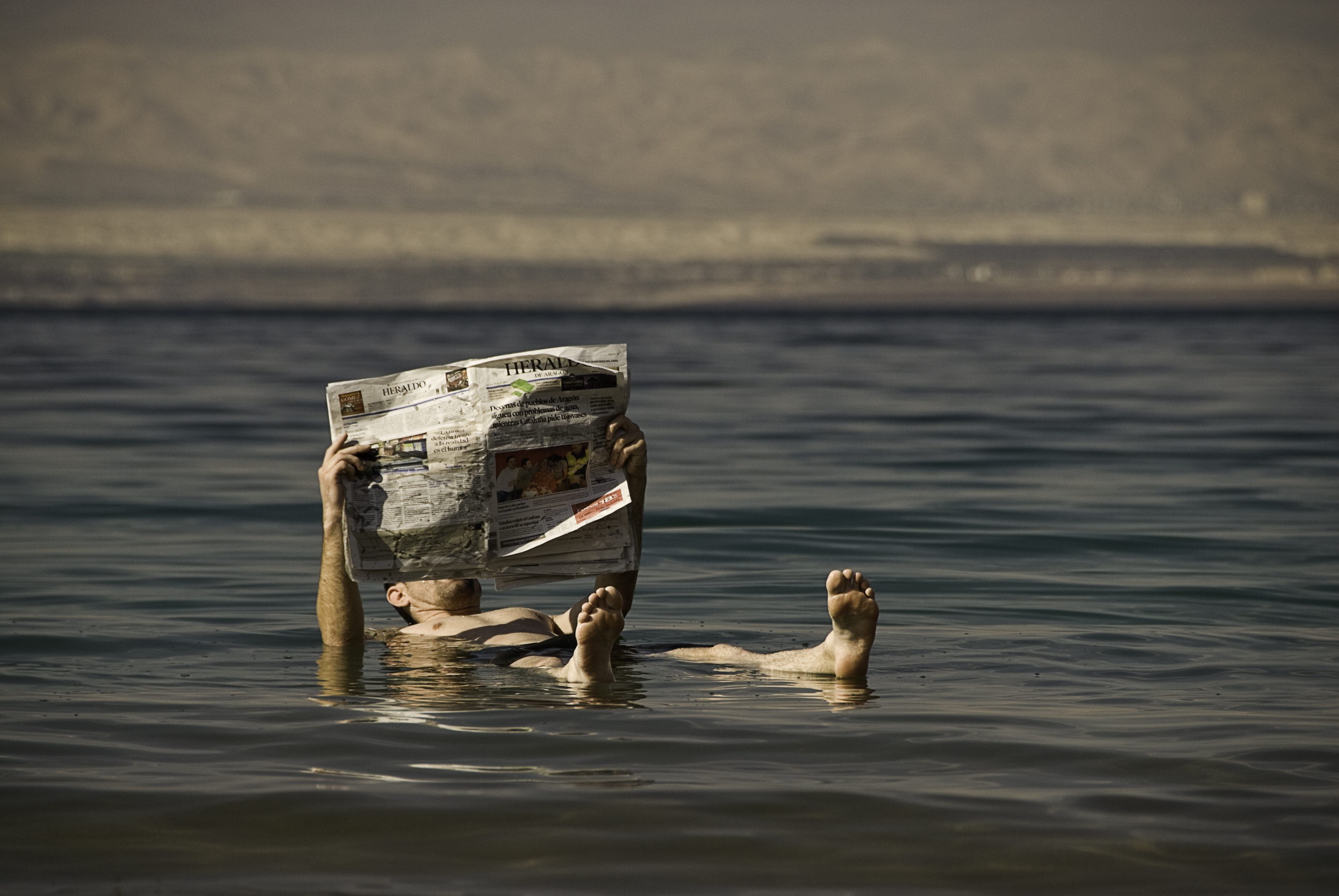 a man floating in the water reading a newspaper