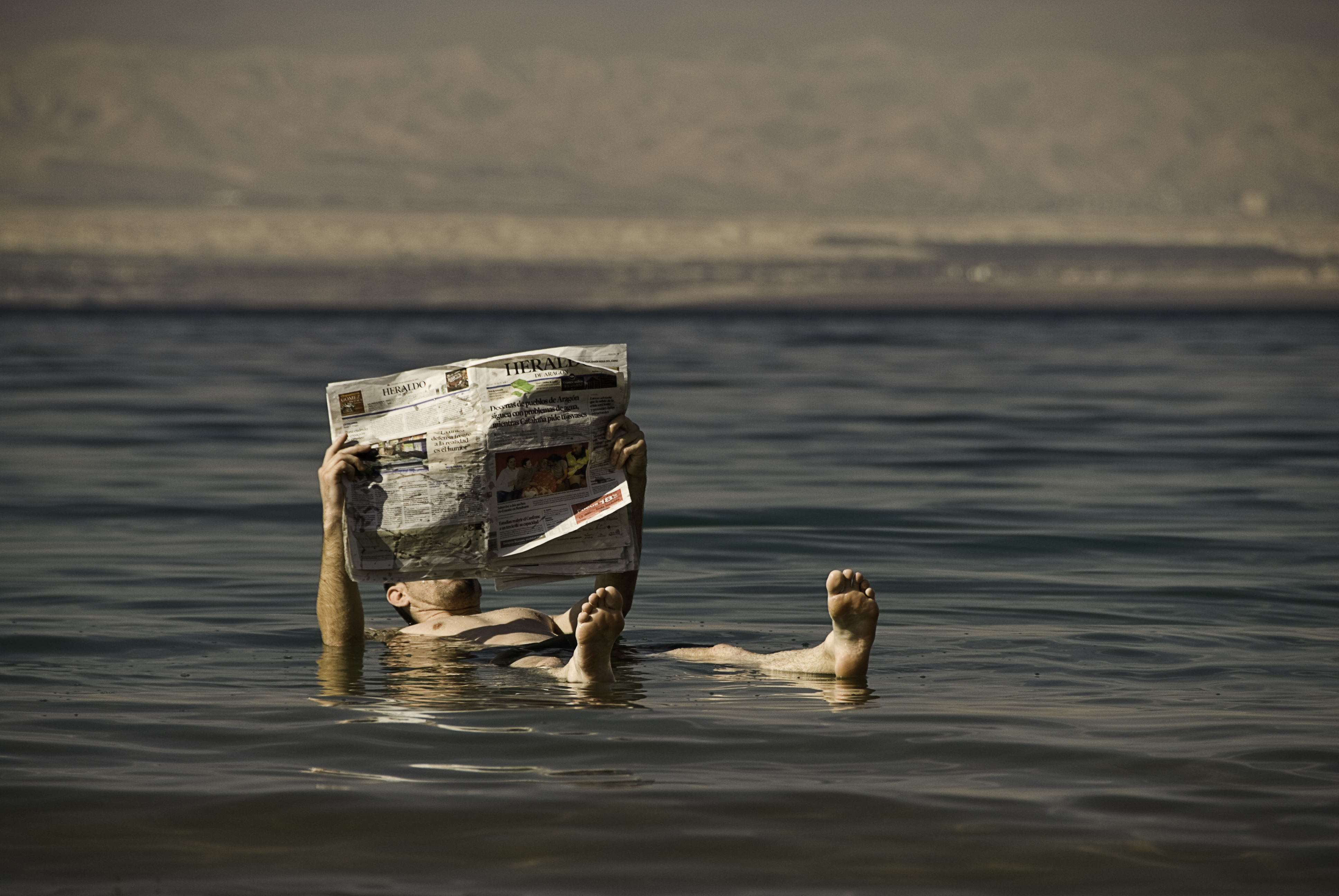Een man leest een krant en drijft in het water