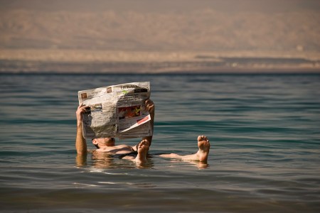 a man floating in the water reading a newspaper
