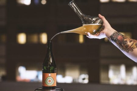 A mixed-fermentation beer from Crooked Run being poured from a glass vessel into a bottle