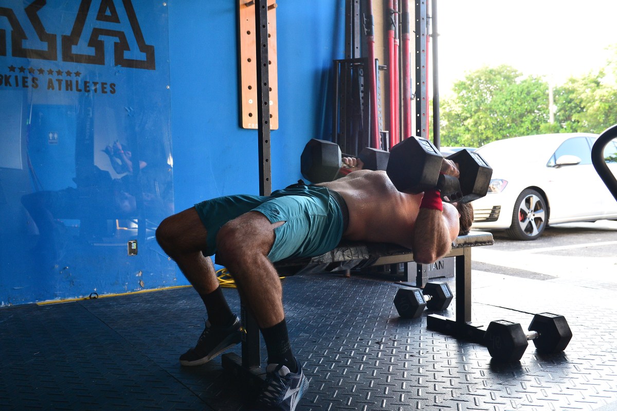 A guy lifting at a CrossFit gym with huge dumbbells.