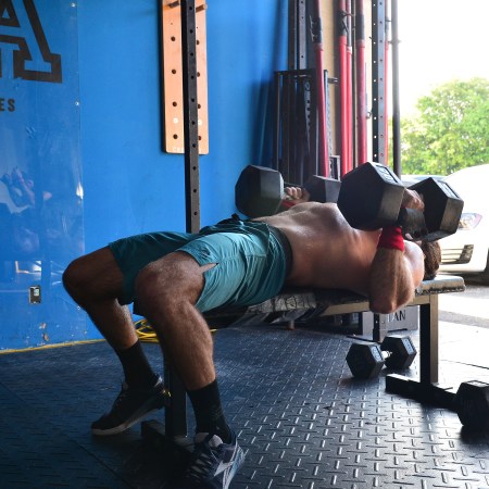 A guy lifting at a CrossFit gym with huge dumbbells.