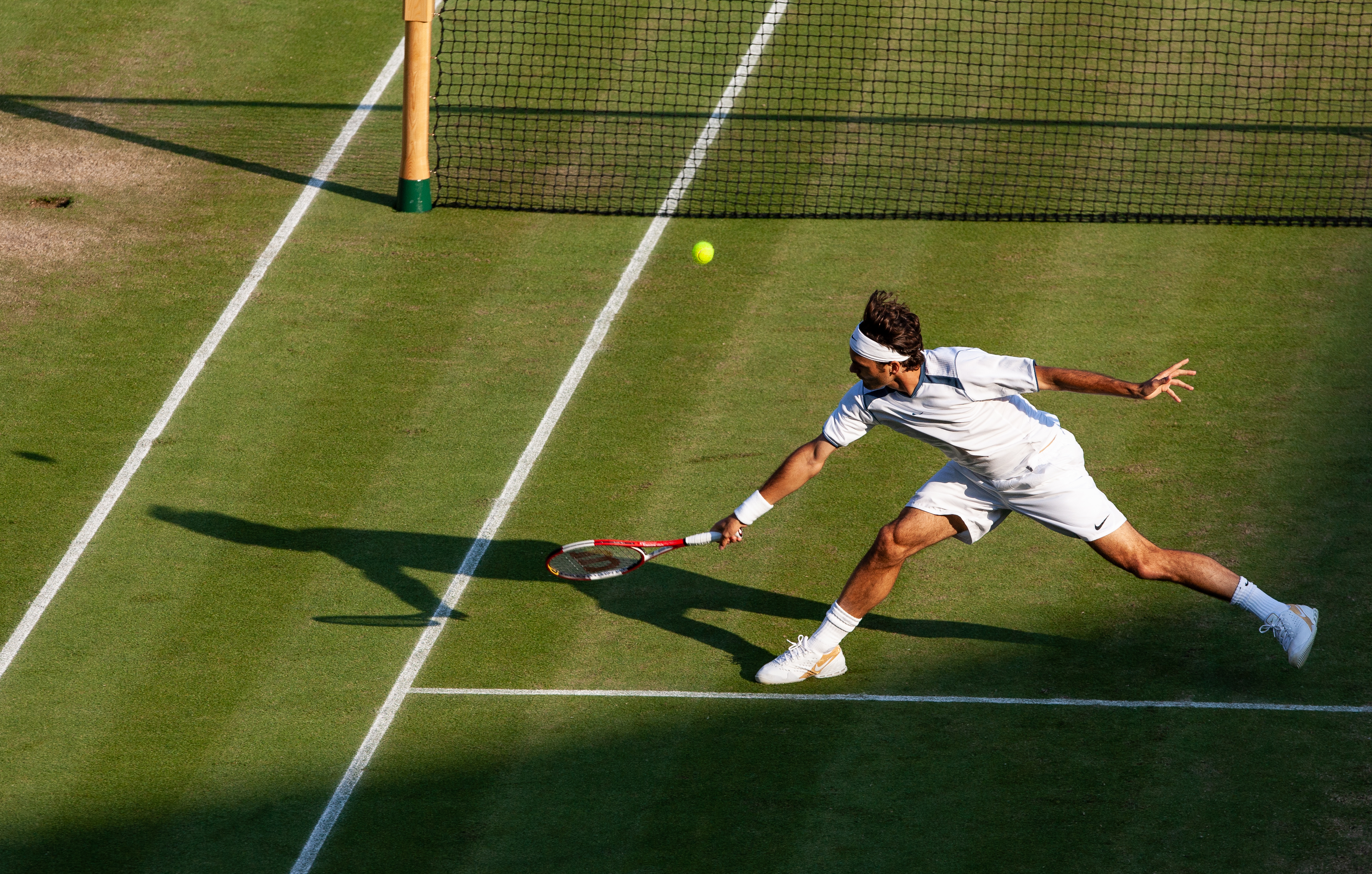 A shot of a young Roger Federer making a remarkable play, fully outstretched to the ball.