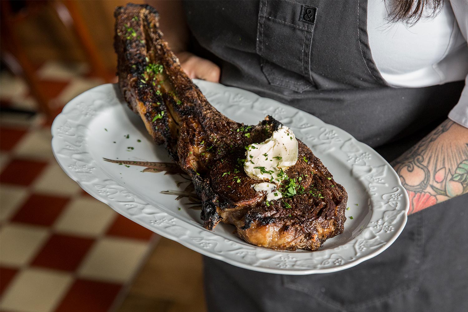 A waiter holding an ax handle steak at St. Anselm, one of the best steakhouses in Washington, D.C.