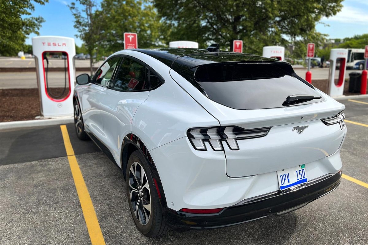 A white Ford Mustang Mach-E at a Tesla Supercharger charging station.