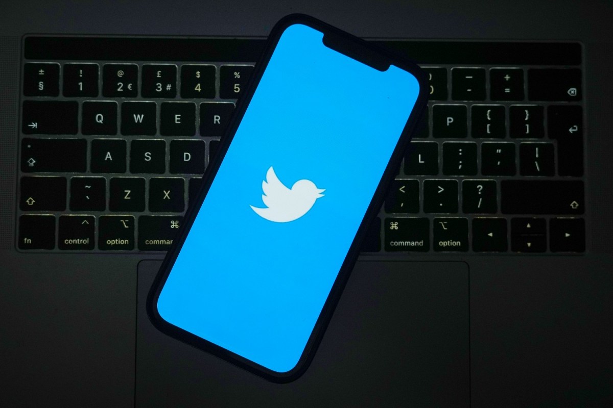 Twitter logo seen on a smartphone, which is sitting on top of a computer keyboard