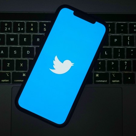 Twitter logo seen on a smartphone, which is sitting on top of a computer keyboard