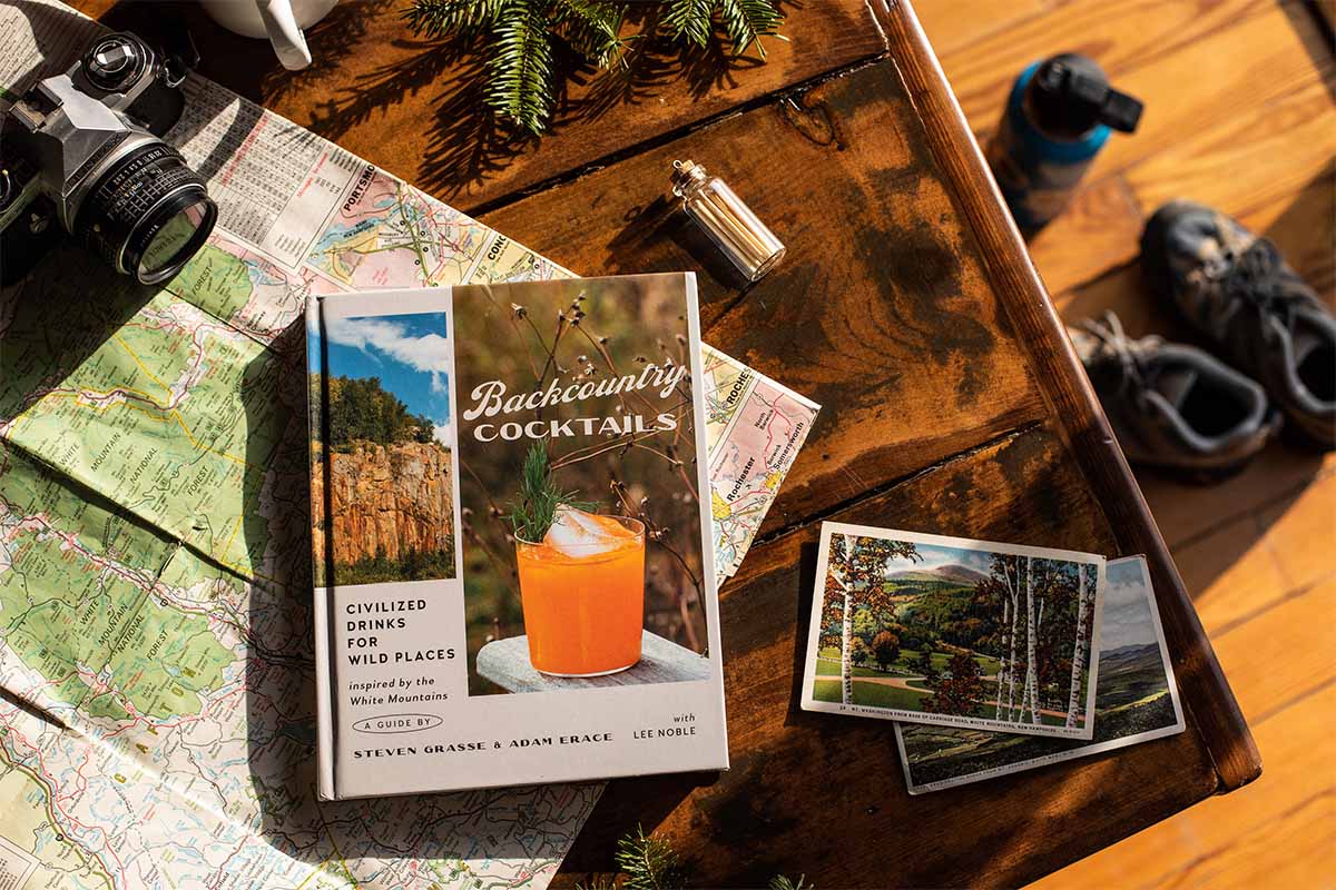 In the book "Backcountry Cocktails," here pictured ona. table with a map and a camera, you'll learn skills from foraging cocktail ingredients to getting out of bear attacks