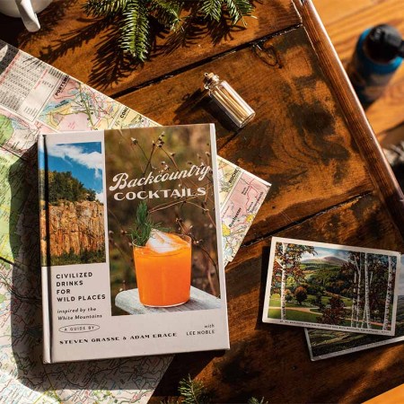 In the book "Backcountry Cocktails," here pictured ona. table with a map and a camera, you'll learn skills from foraging cocktail ingredients to getting out of bear attacks