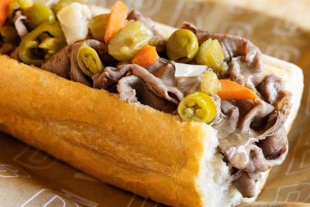 beef sandwich with banana peppers, onions and carrot on a roll
