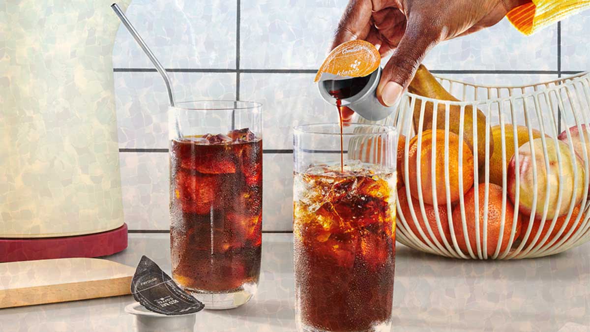 A person pouring a Cometeer coffee capsule in a glass with ice.