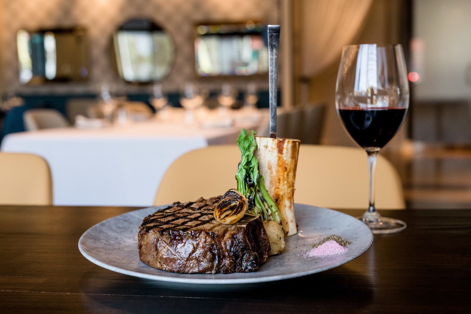 Plated steak next to a glass of red wine.