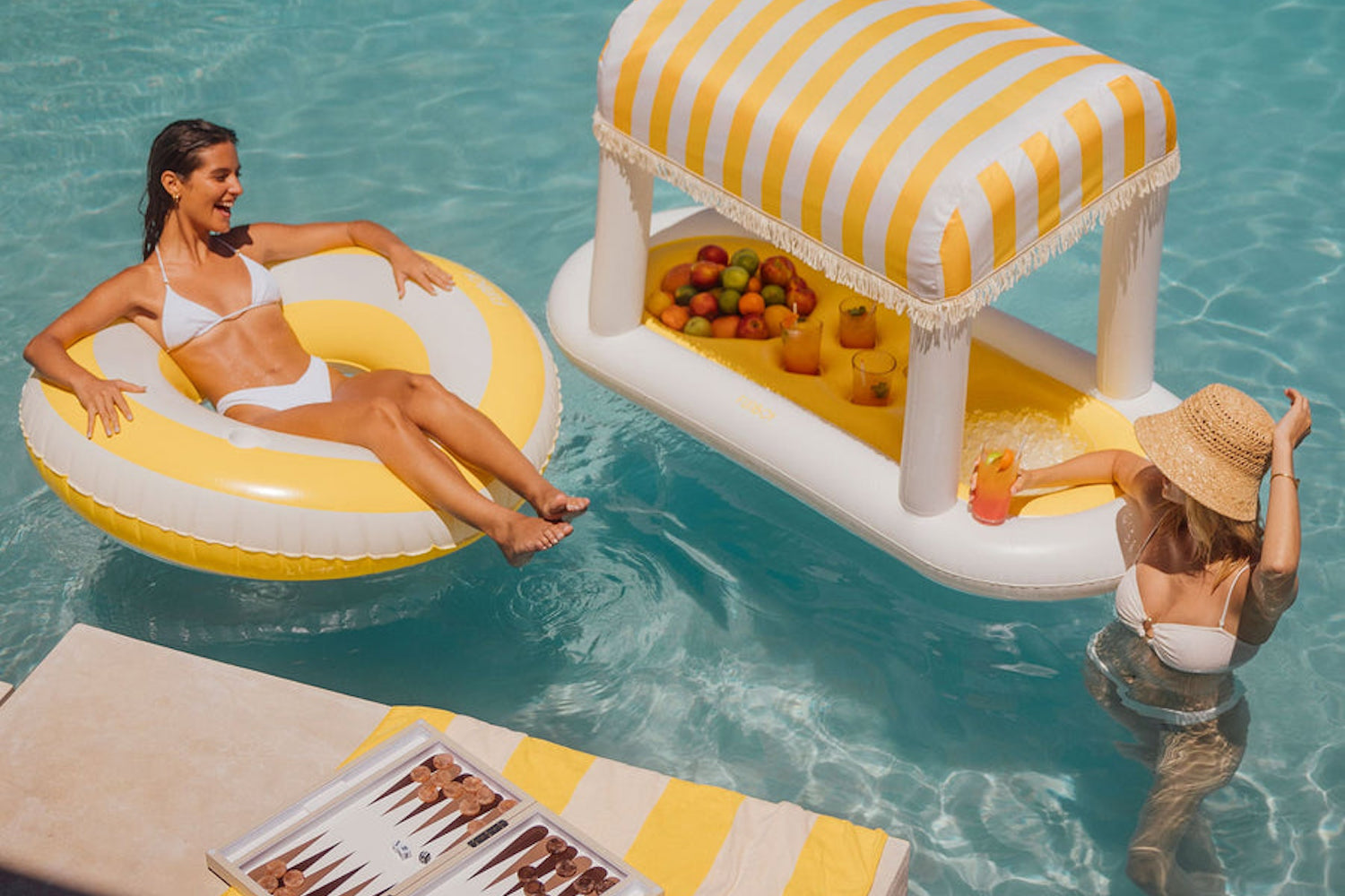 two women in a pool near a FUNBOY Yellow Cabana Floating Bar Float