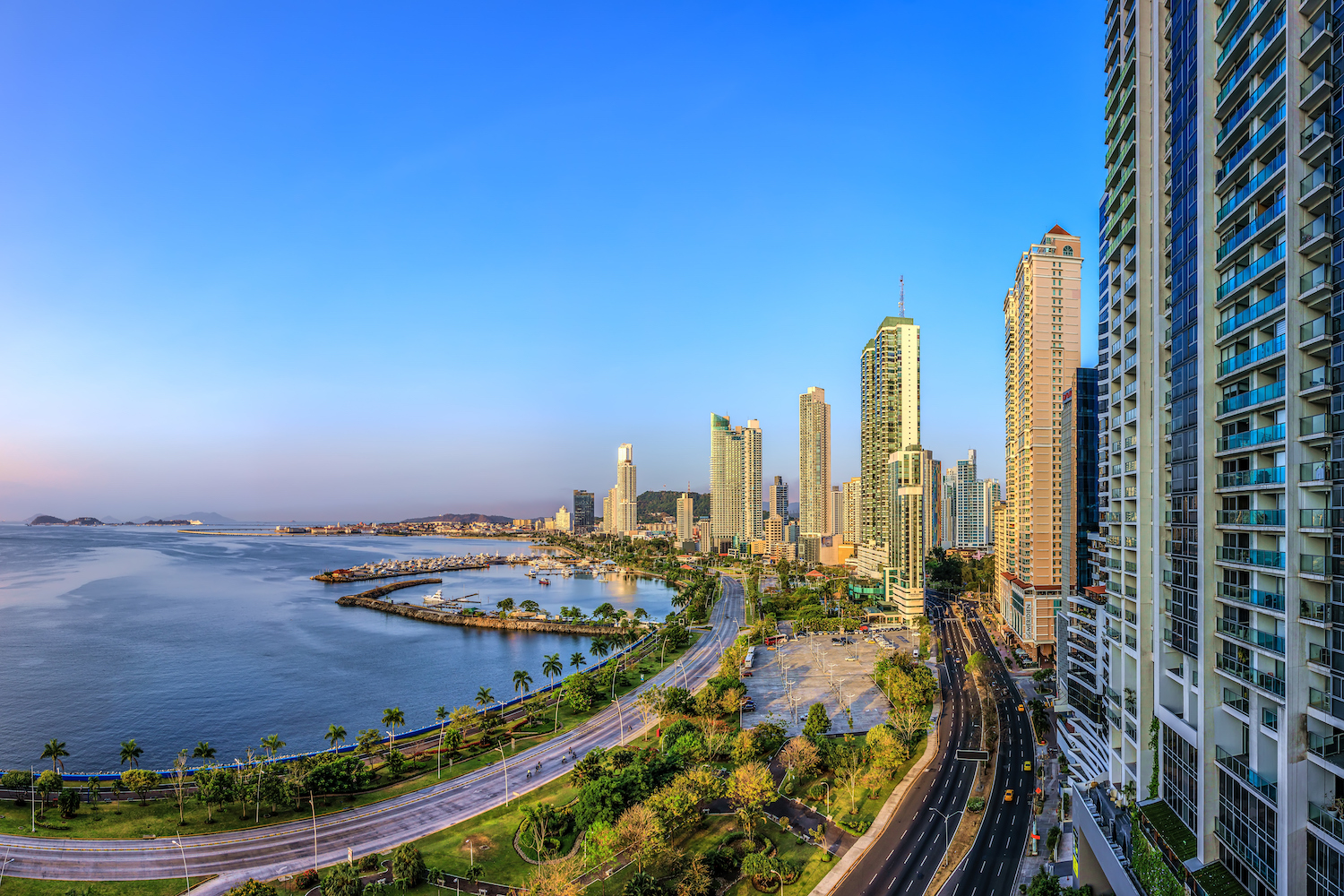 Panoramic high level view of Panama City, high buildings against blue sky, in front blue sea.