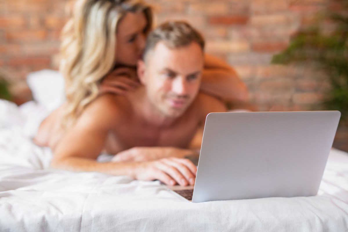 Couple lying in bed and using laptop computer together