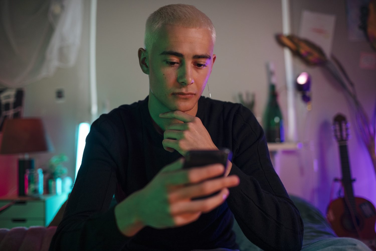 A person with hand on their chin looking at their phone.