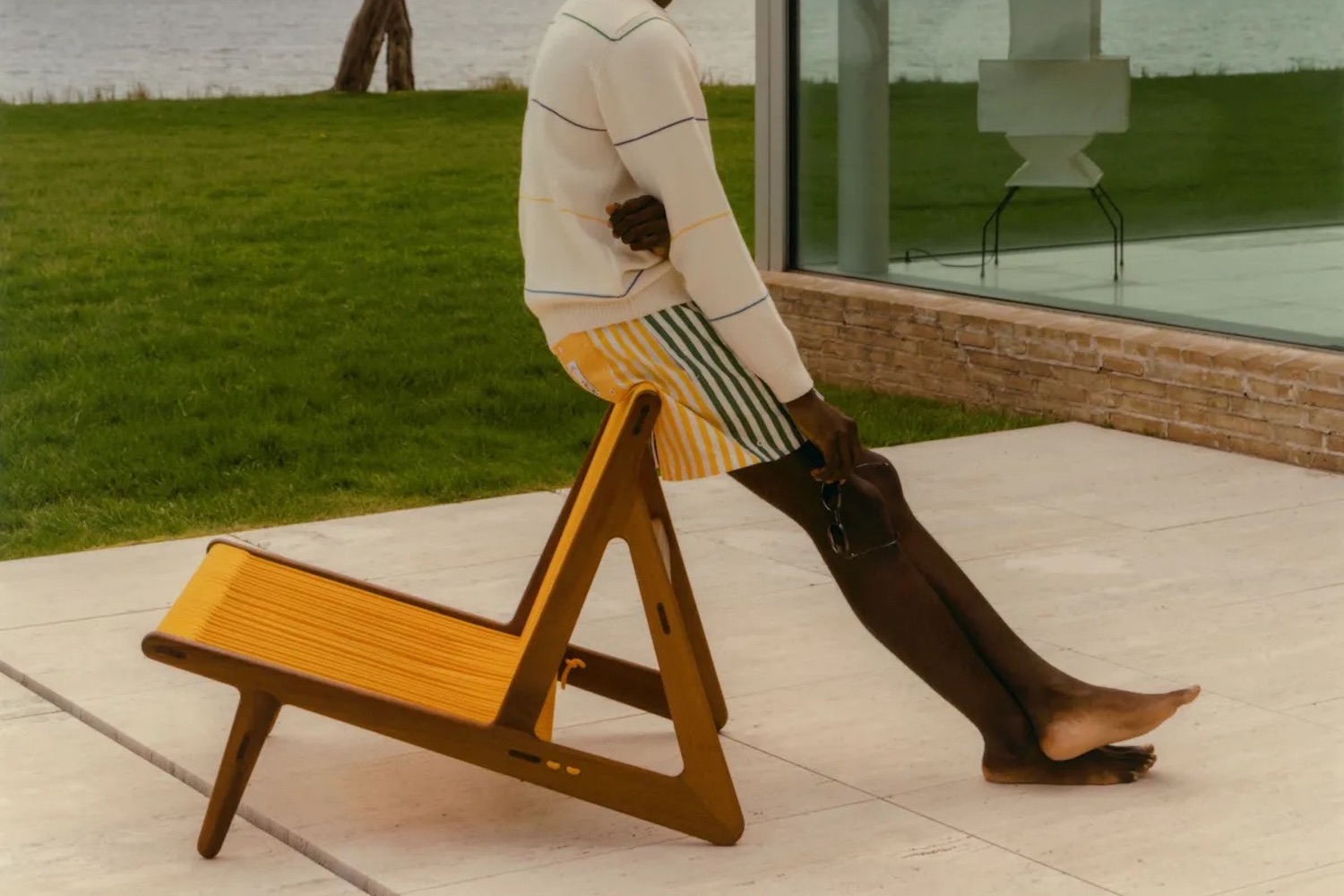 a model leaning against a GUBI x Noah chair