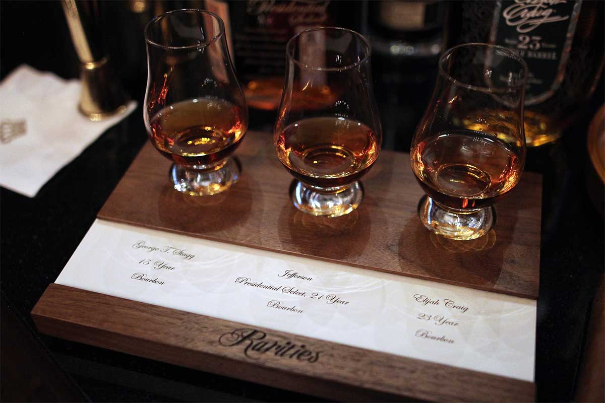 Three pours of rare bourbon on a tasting mat at the NYC bar Rareties. Some bourbons, while high quality, are way too much money to spend on.