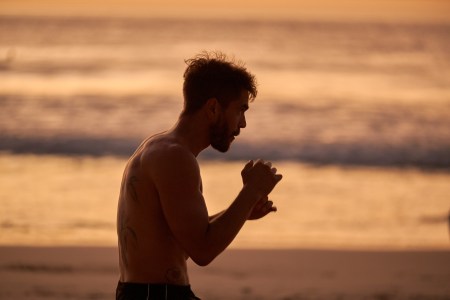 A man shadow-boxing at the beach.
