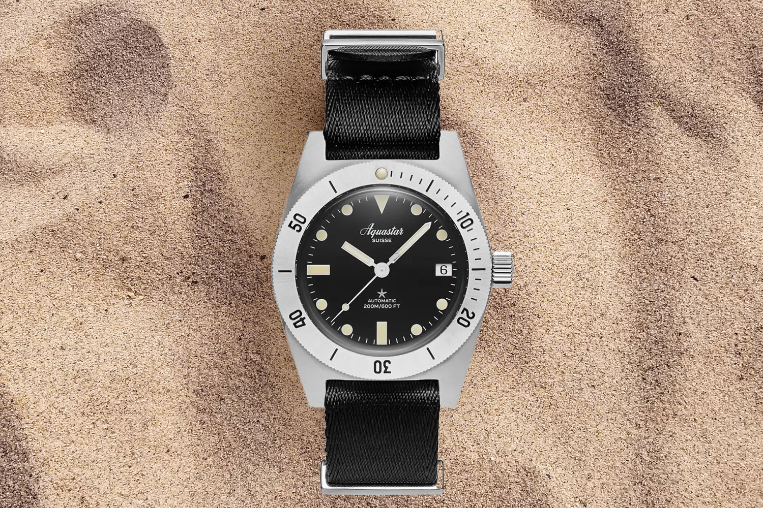 Black colored watch in the sand.