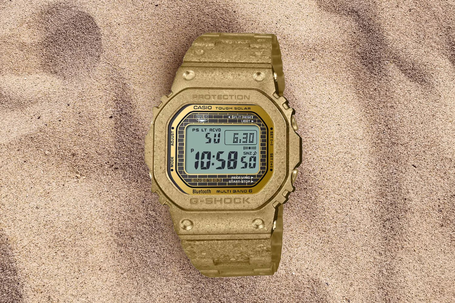 gold colored watch in the sand.