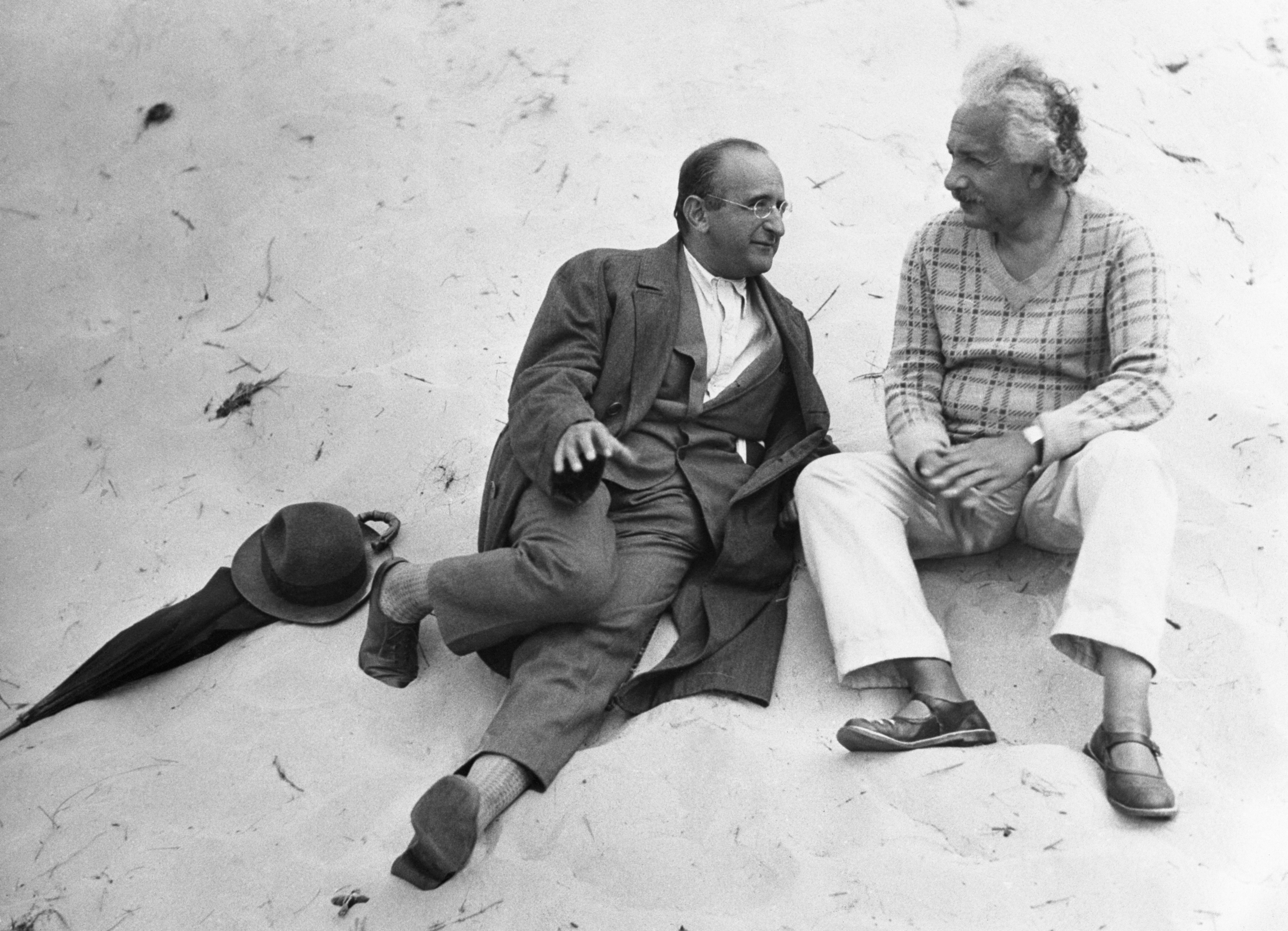 Albert Einstein sitting on a beach with his colleague.