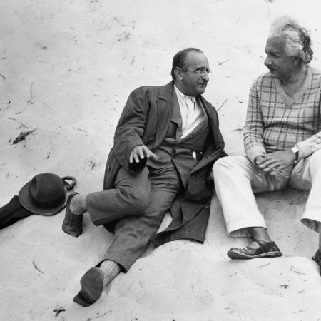 Albert Einstein sitting on a beach with his colleague.