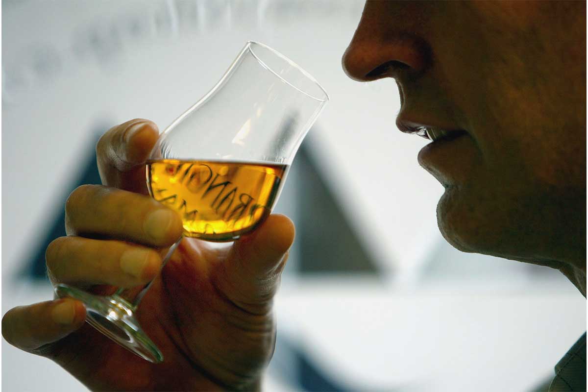 Whisky exporter Allan Scott uses a nosing glass to test the quality of one of his brands in his shop, March 16, 2004, in Glasgow, Scotland