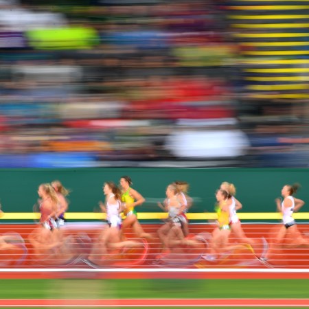 A group of elite runners on a track, in a speedy blur.