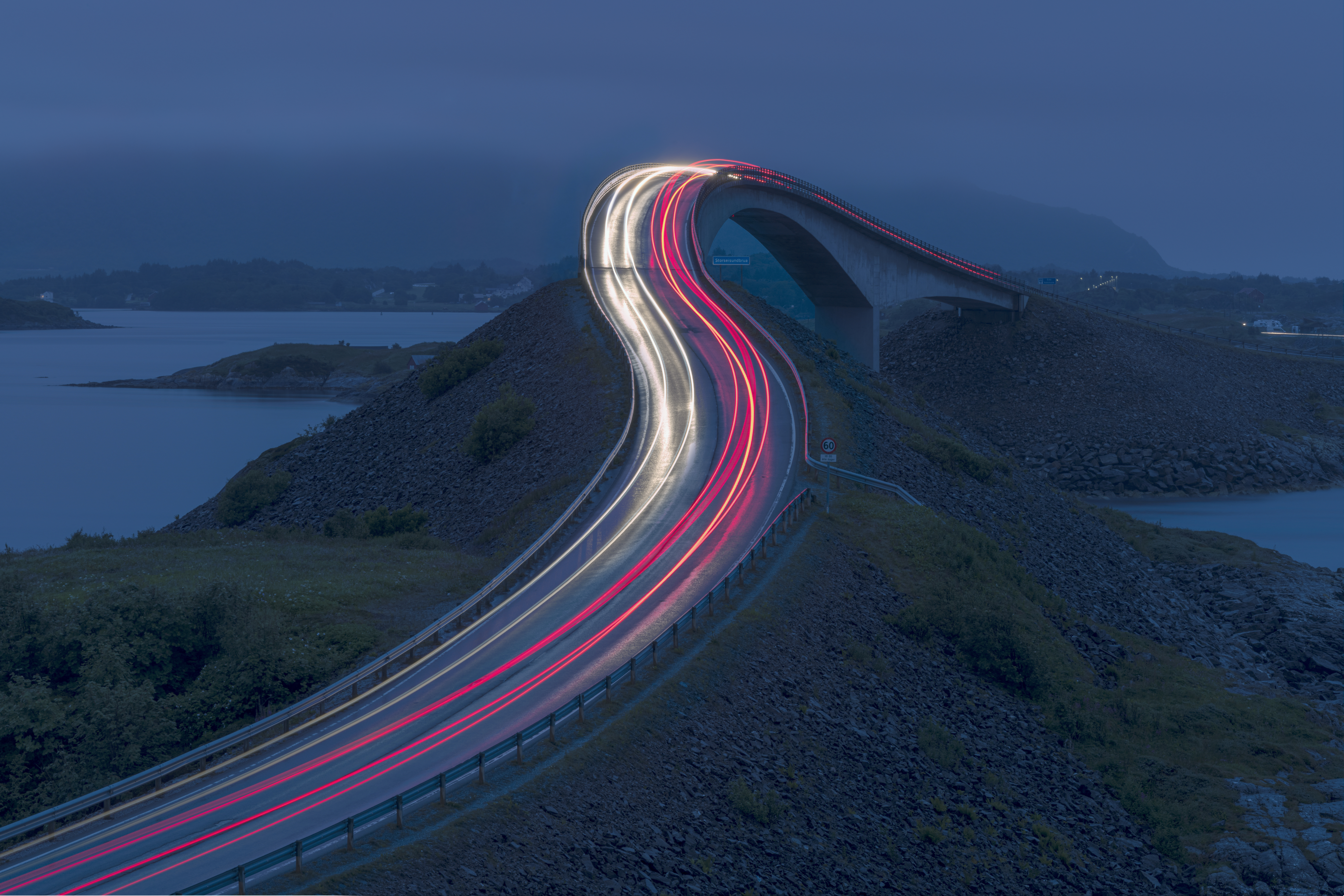 The streaking lights of cars on a beautiful Norway road at night.