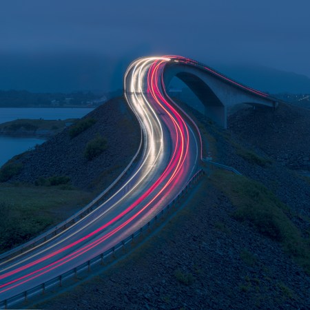 The streaking lights of cars on a beautiful Norway road at night.