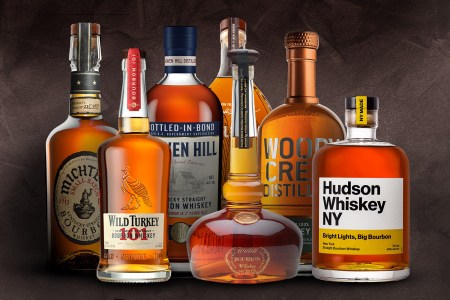 a lineup of bourbon bottles on a textured grey background